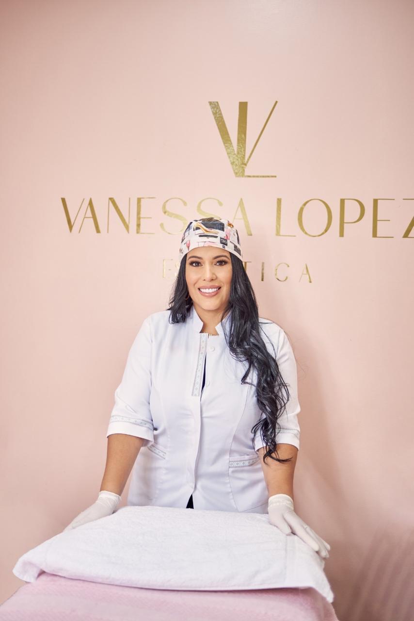 Vanessa López en bata blanca frente al letrero dorado de su estética